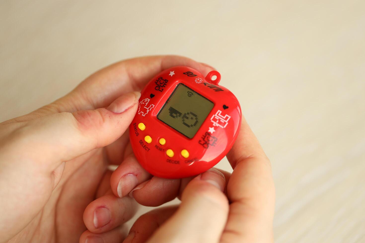 Kyiv, Ucrania - marzo 9, 2024 retro mascota llavero juego tamagotchi en rojo el plastico caso en hembra manos foto