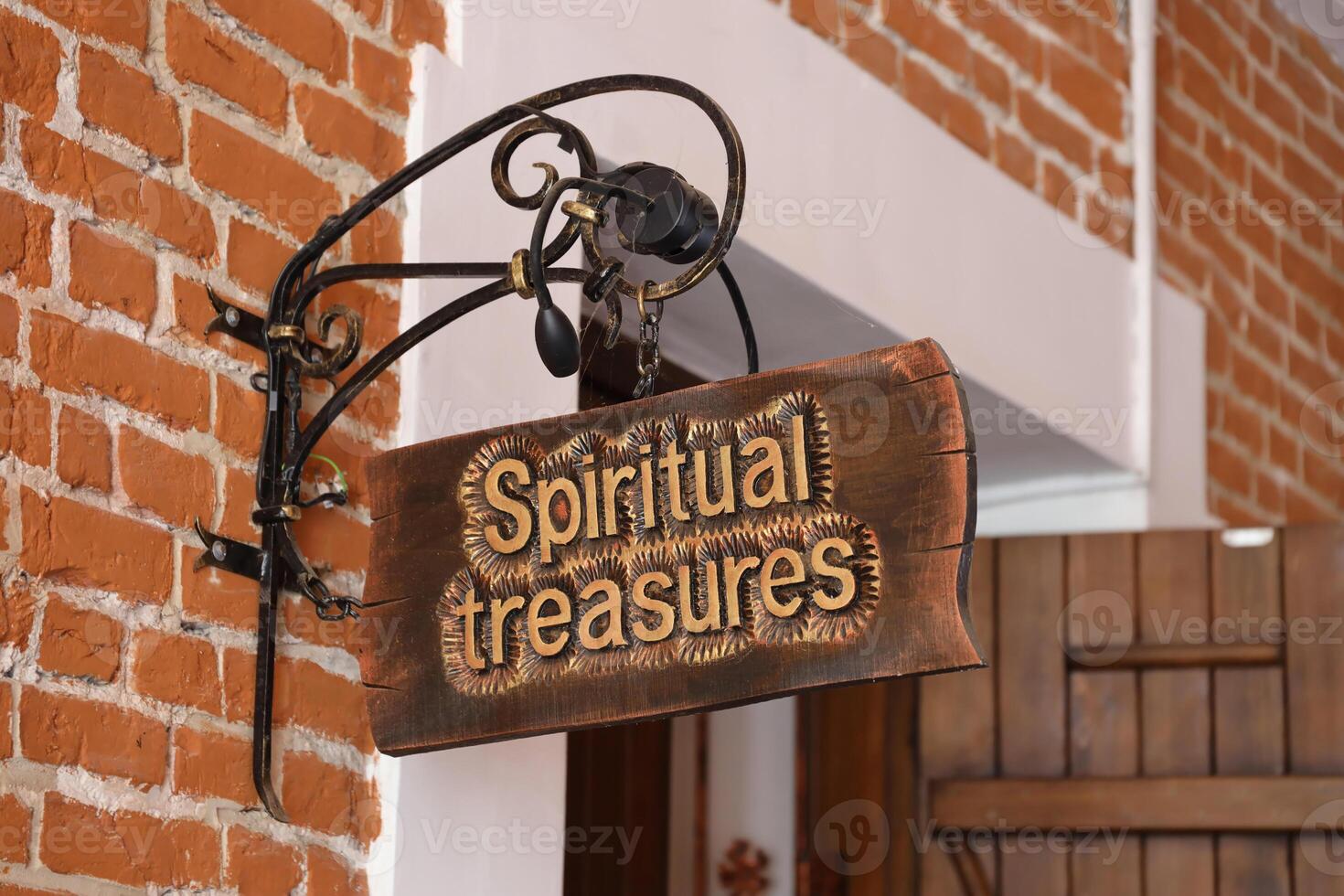 Old wooden sign on the background of the old castle walls, vintage image with Spiritual Treasures sign photo