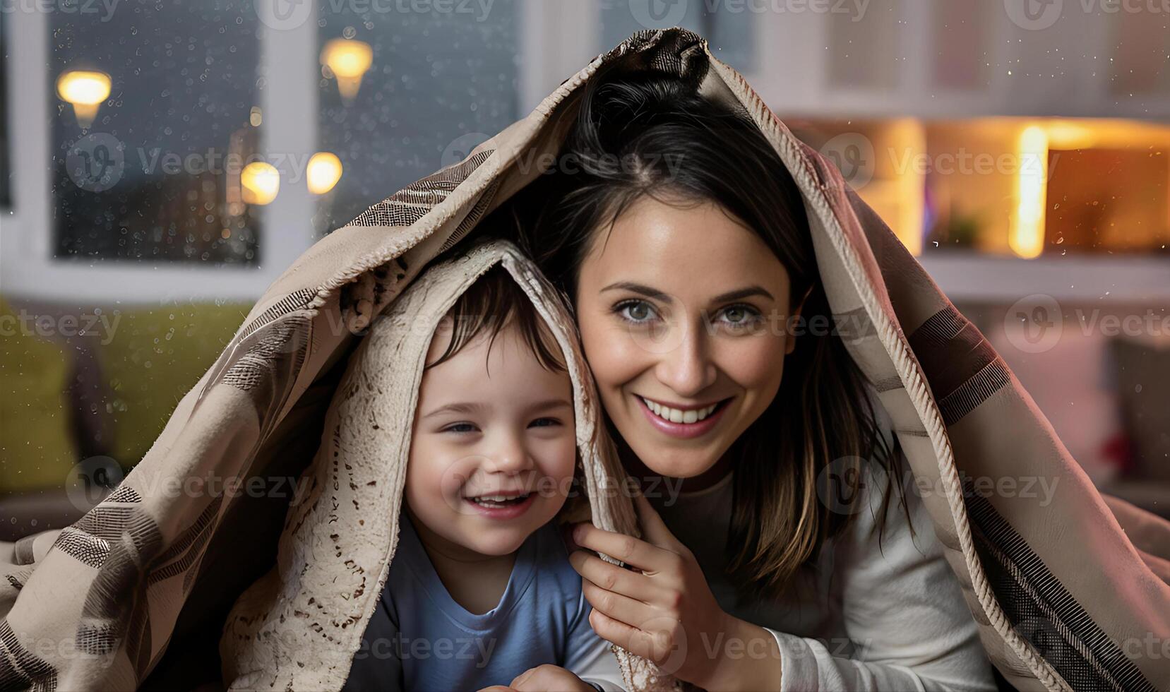 madre y niño son jugando debajo un cobija foto