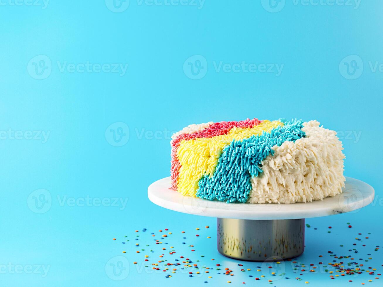 Shag cake on blue background. Colorful vanilla shag cake with perfect vanilla buttercream. Idea of visually striking cake decorating schemes, trendy cake, copy space. photo