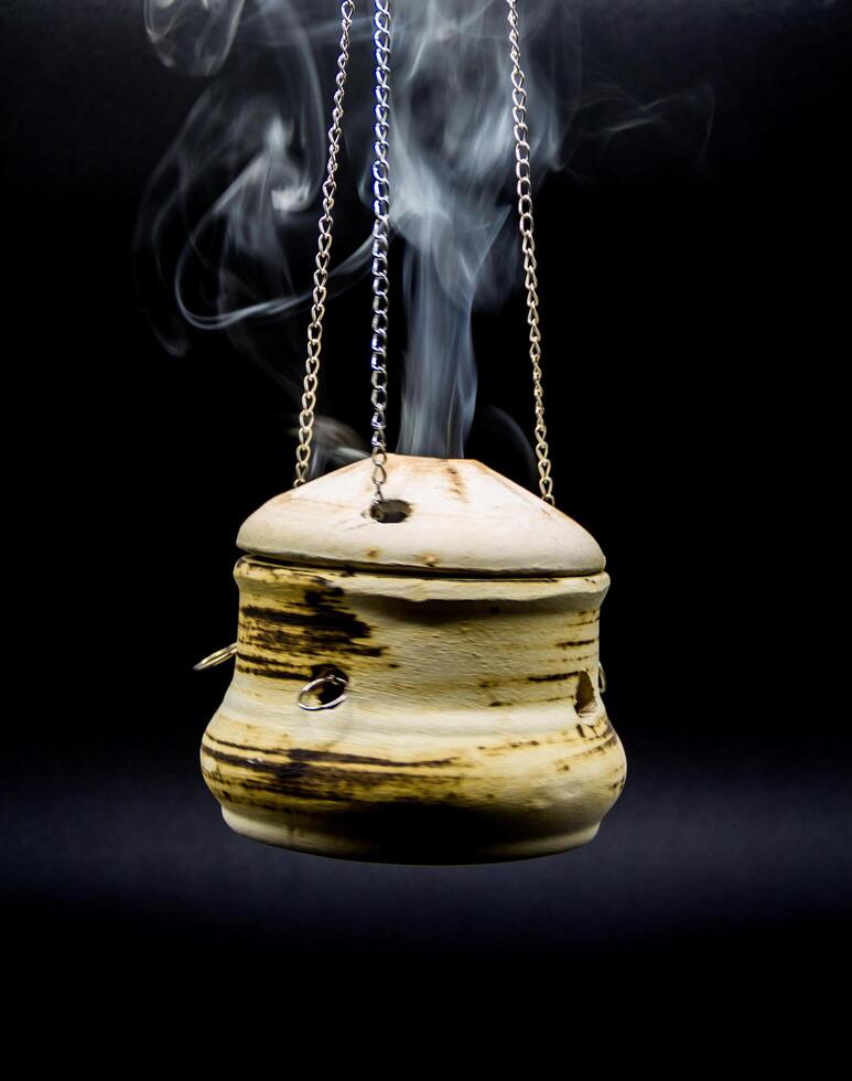 bowl of incense hanging smoke on black background photo