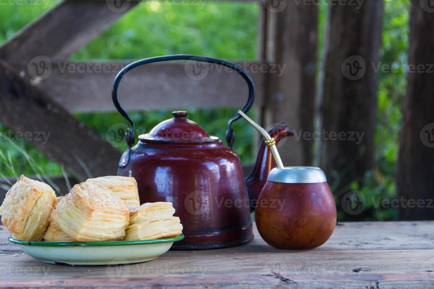 Mate and kettle with a plate of salty Argentine biscuits and yerba mate infusion photo