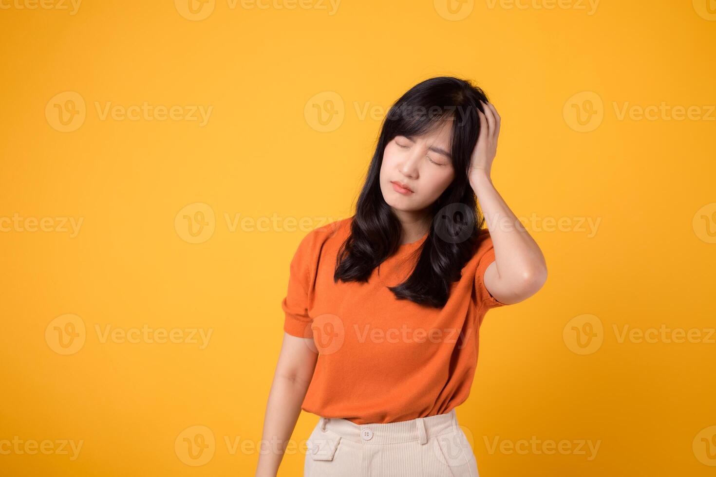 Capture the complexity of emotions with a portrait of a stressed woman, her face revealing pain, sadness, and tension. isolated on yellow background. photo