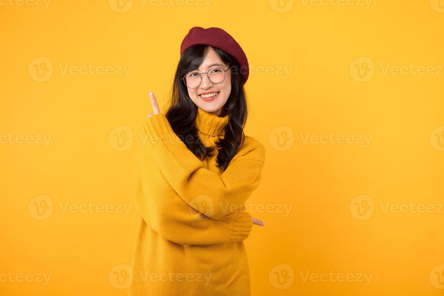 young Asian woman in her 30s, wearing a yellow shirt and red beret. happy face and pointing finger to free copy space against vibrant yellow backdrop. Unlock savings and shop now photo