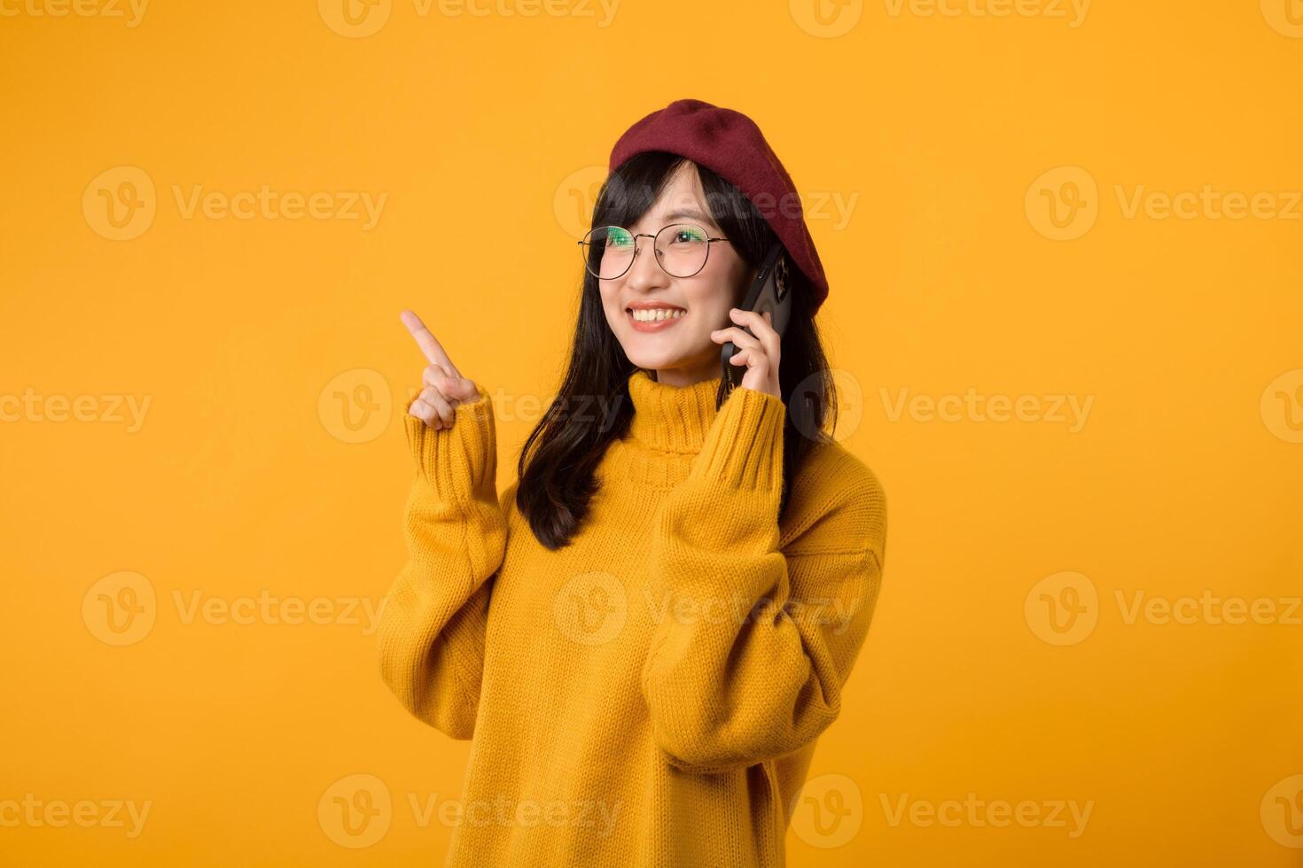 Portrait young pretty asian woman 30s wearing yellow sweater and red beret feeling happy while using smartphone explore the world. mobile application concept. photo