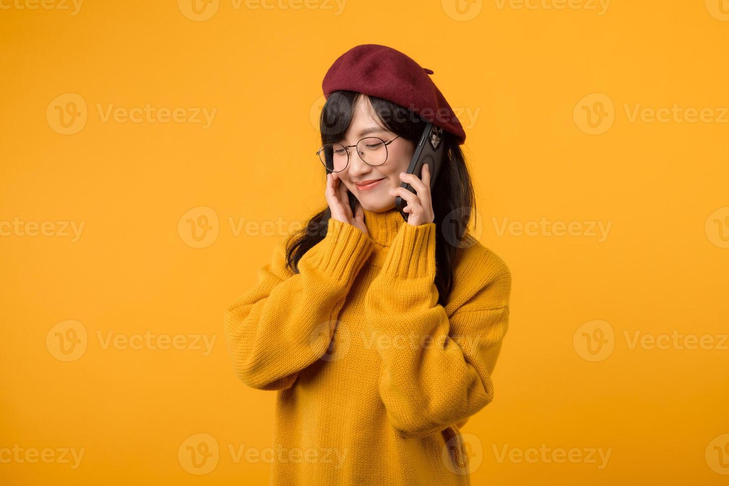 Portrait young pretty asian woman 30s wearing yellow sweater and red beret feeling happy while using smartphone explore the world. mobile application concept. photo