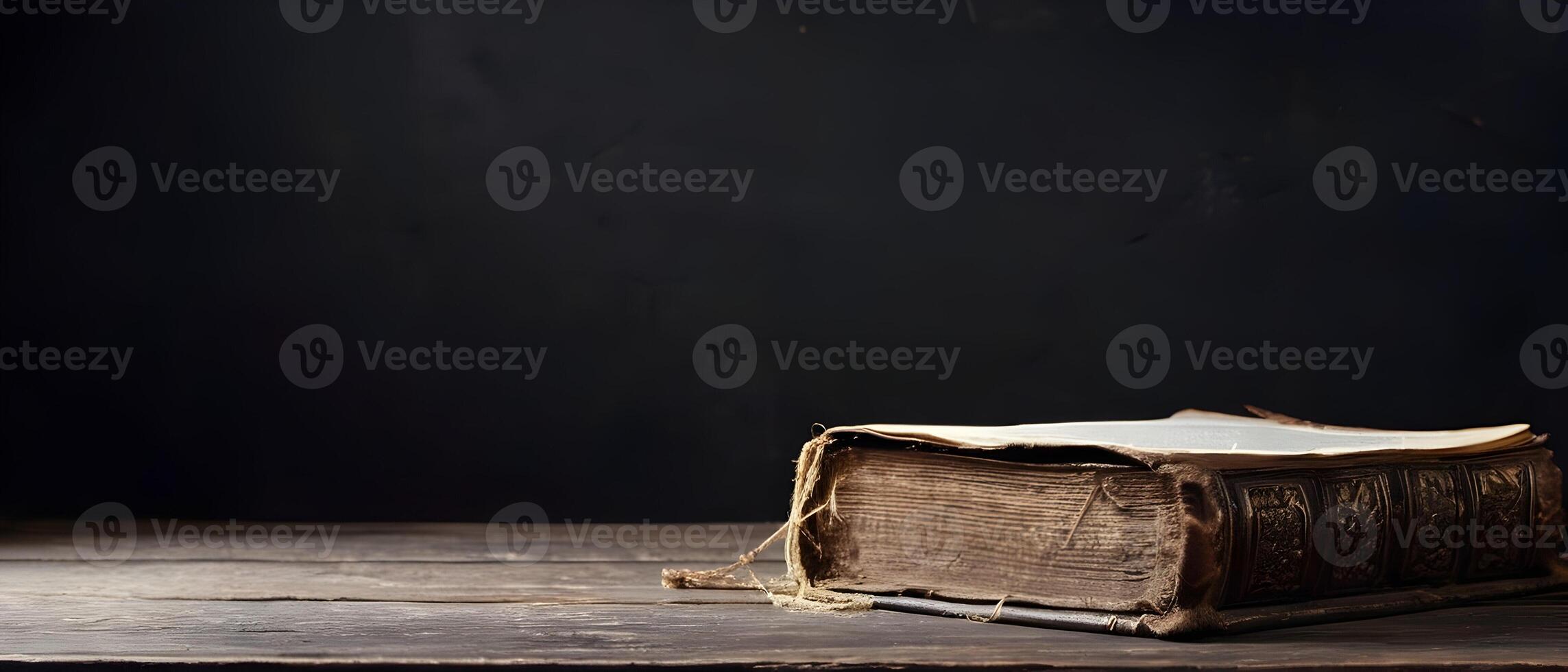 Old holy bible on old rustic vintage wooden table and black wall. Church faith Christian background banner panorama photo