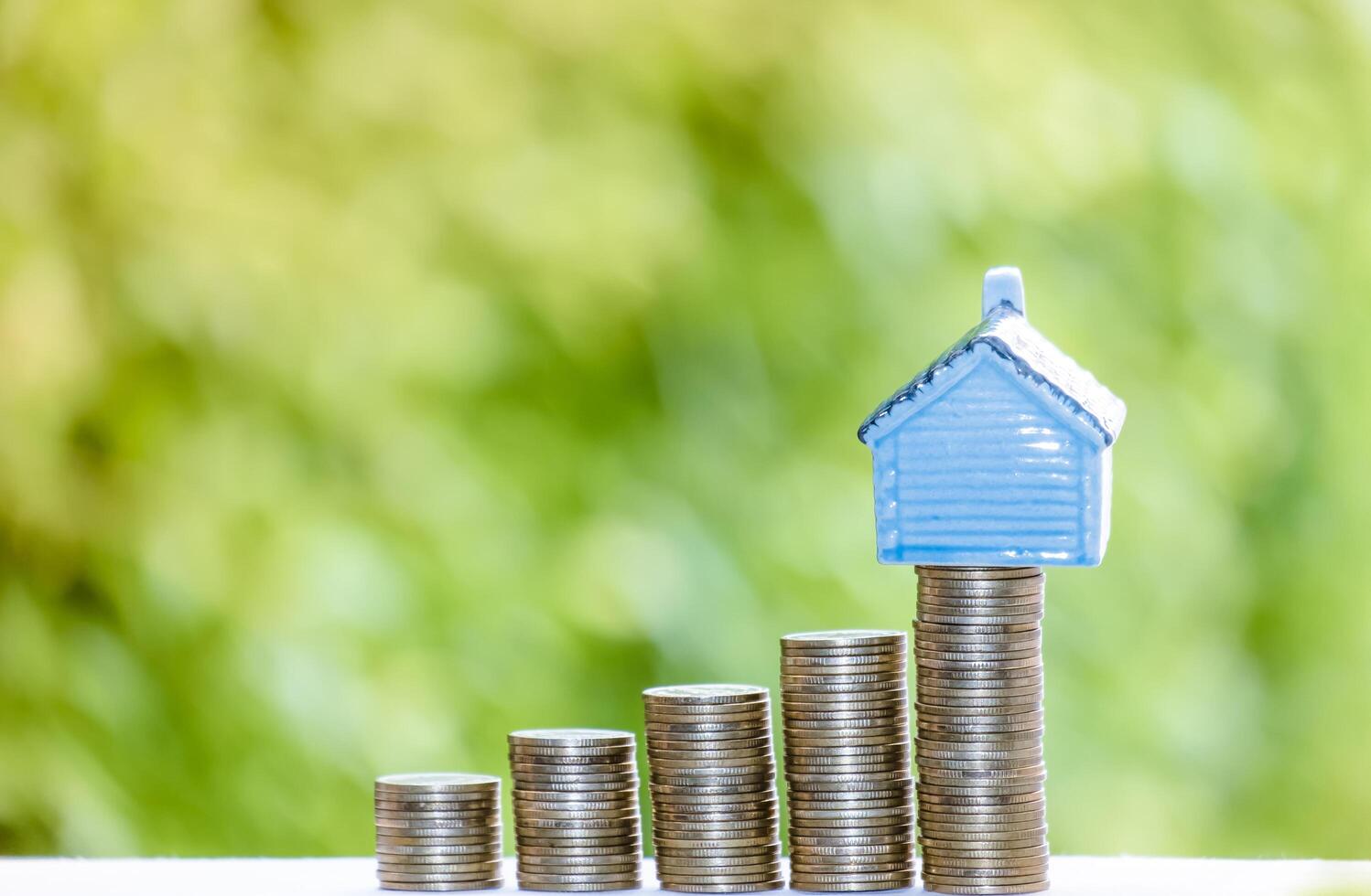 House model and coins money, Business Finance coin stack growing graph with green tree bokeh background,investment, loans and real estate concept photo