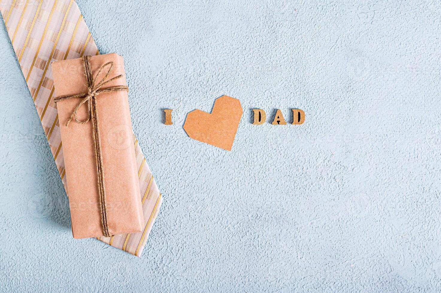 Father's day wrapped gift on tie, heart and lettering on blue background photo