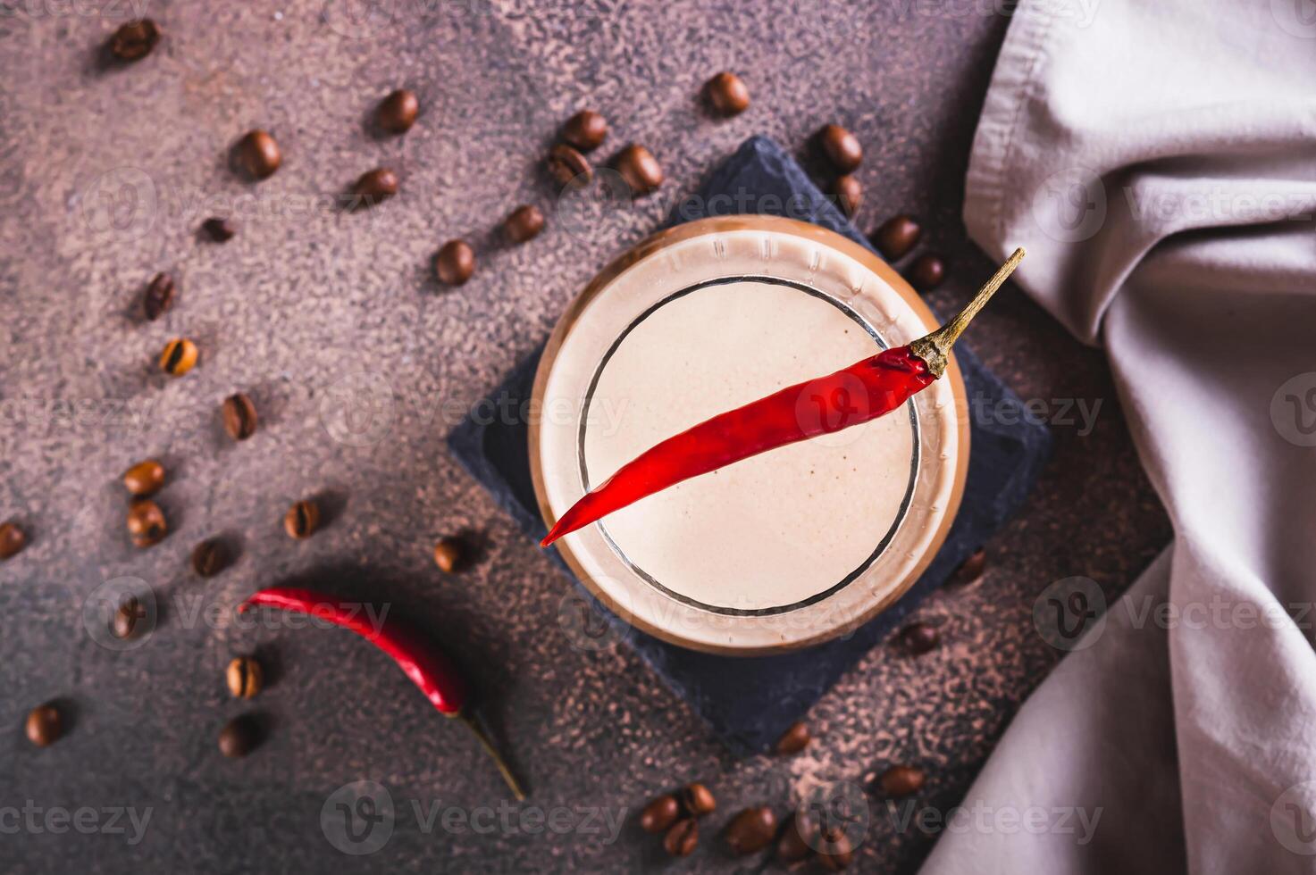 Close up of spicy coffee latte with chili pepper in a glass on the table top view photo