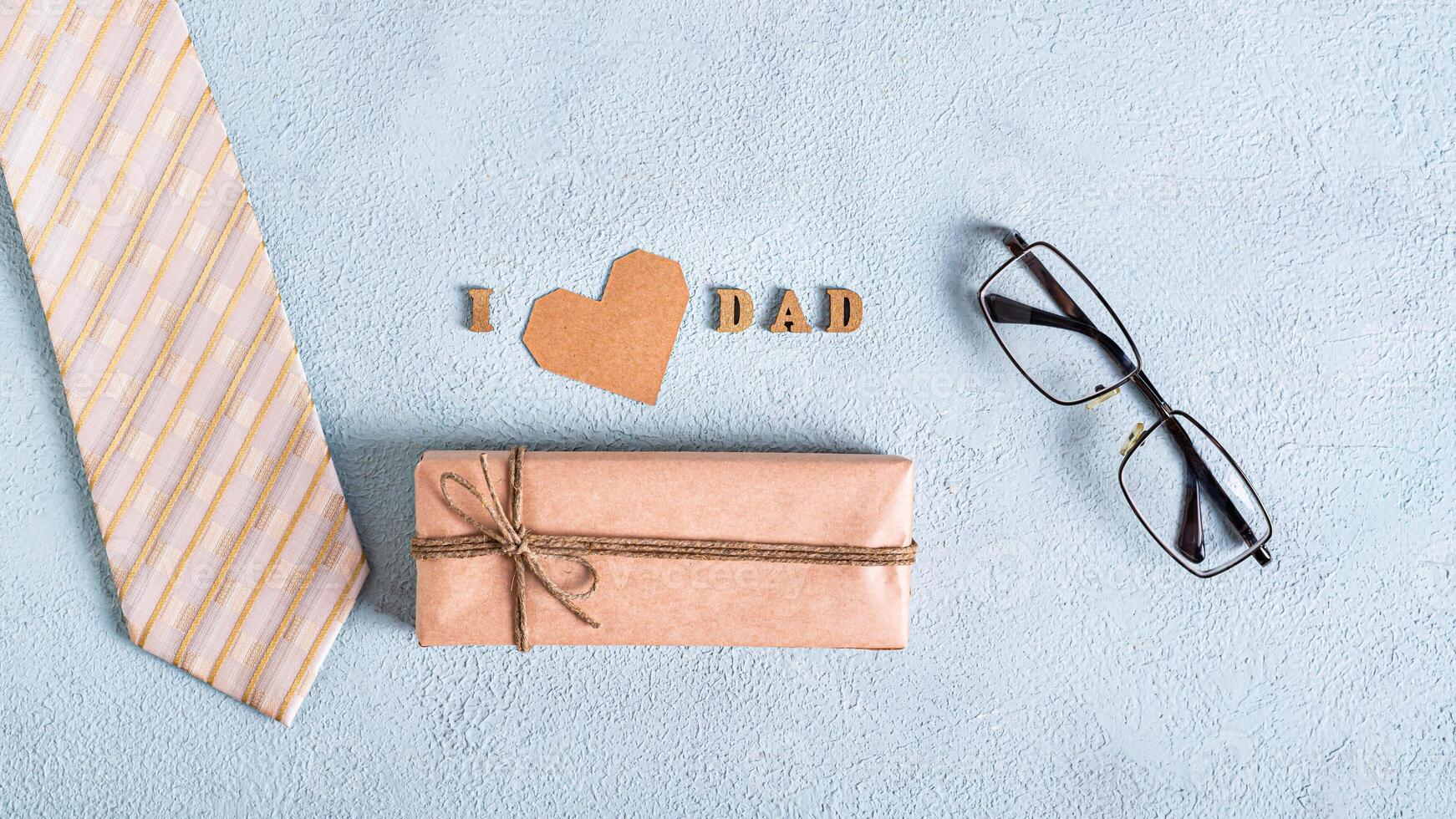 Father's day craft gift, cardboard heart, tie, glasses and inscription on a blue background photo