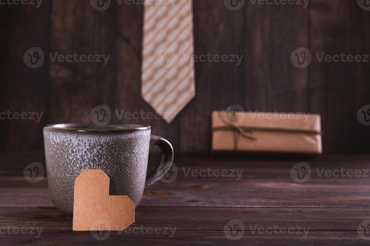 Father's day concept cardboard heart near the mug on the background of a gift and tie on the table photo