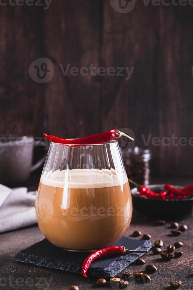 Spicy coffee latte with chili pepper in a glass on the table vertical view photo
