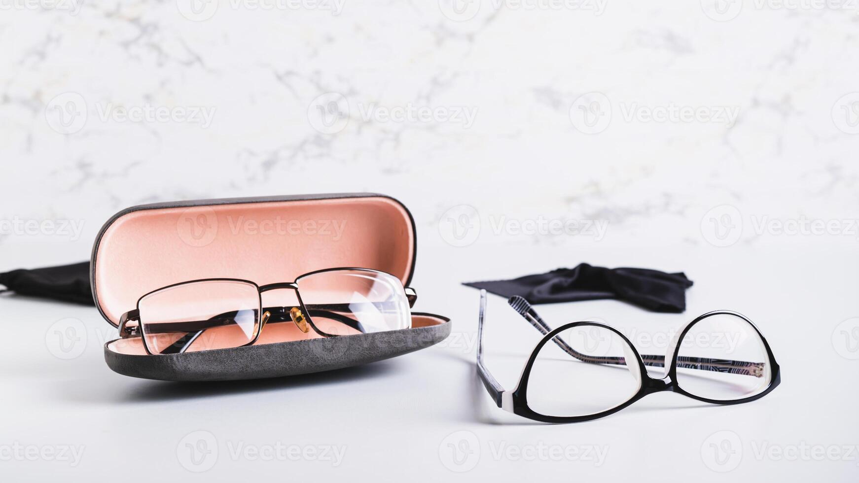 Eyeglasses in an open hard case and eyeglasses on a table photo