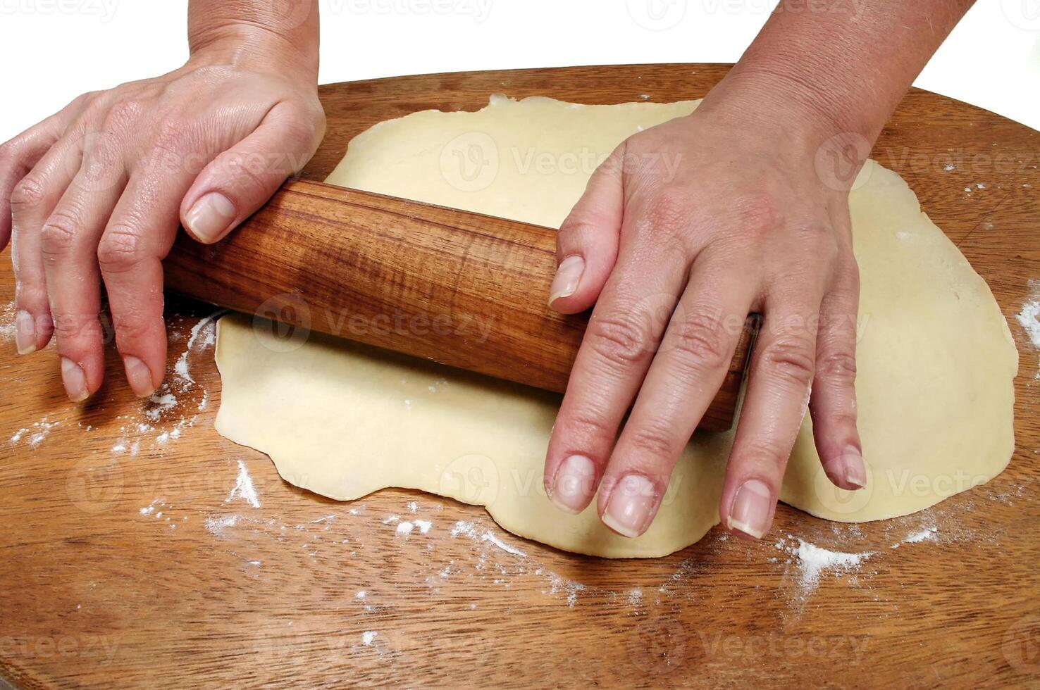 rolling out dough on wooden table to make bread photo