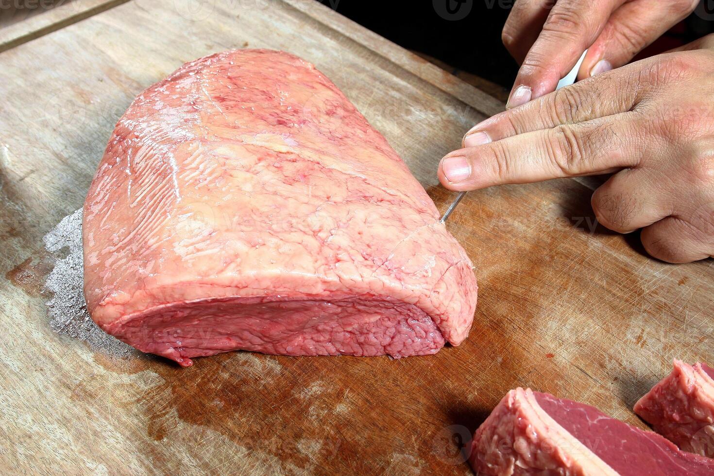 professional butcher teaching step by step how to prepare picanha, a Brazilian cut of meat photo