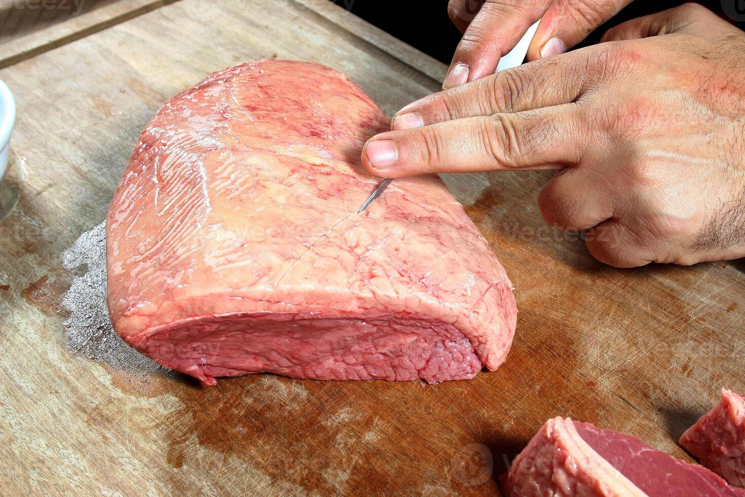 professional butcher teaching step by step how to prepare picanha, a Brazilian cut of meat photo