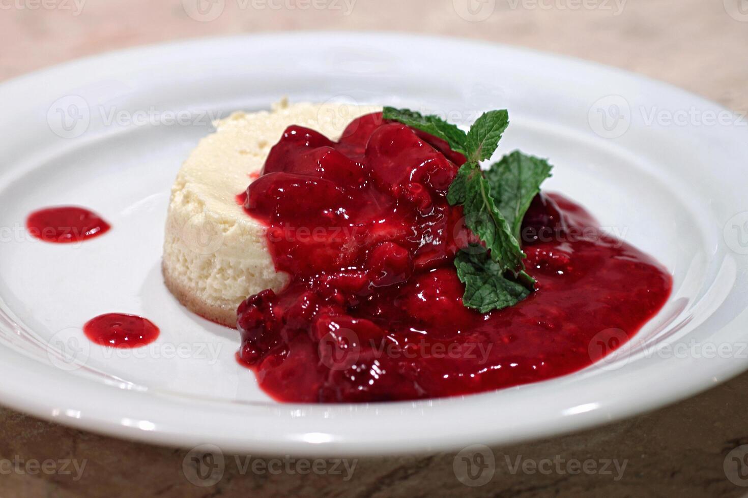 cheesecake with red fruit syrup on plate photo