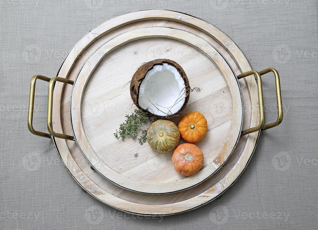 coconut and pumpkins on wooden platter on the table photo