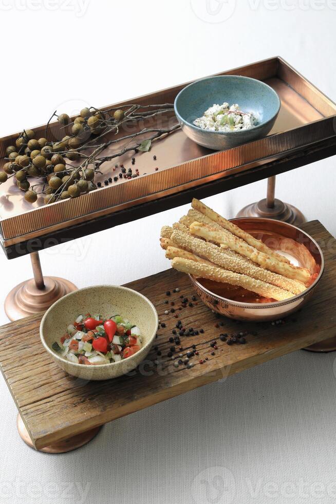 bronze and wooden tray with snacks, pepper and flowers photo