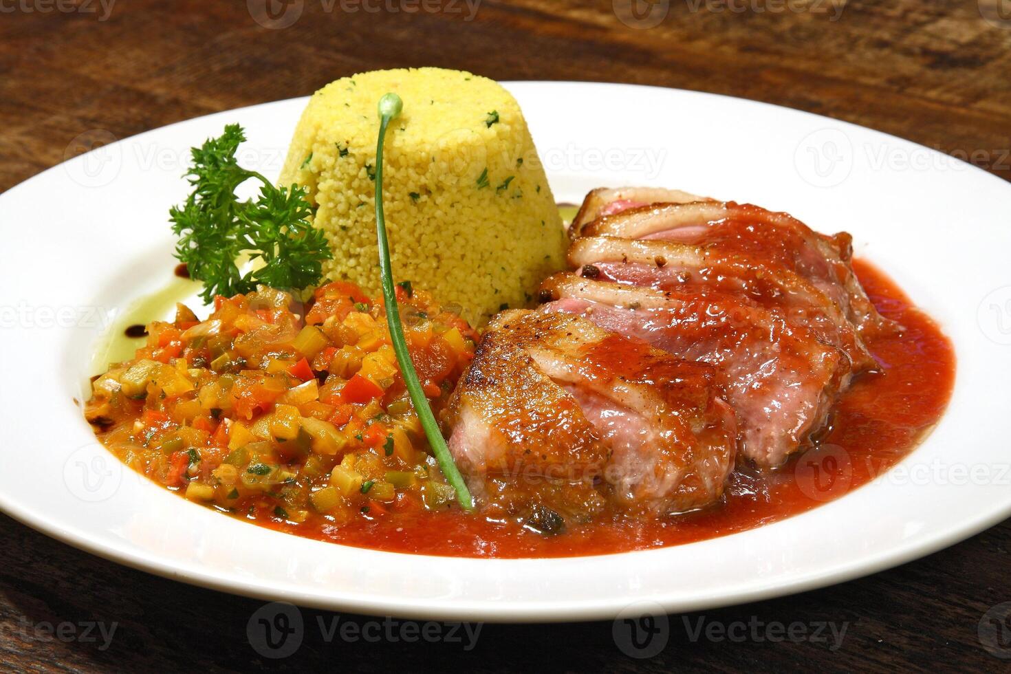 roast duck with sauce and Moroccan couscous on plate photo