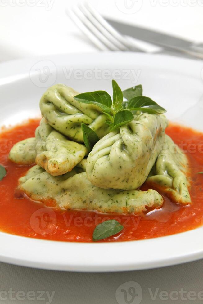 bundle of green pasta with cheese and tomato sauce photo
