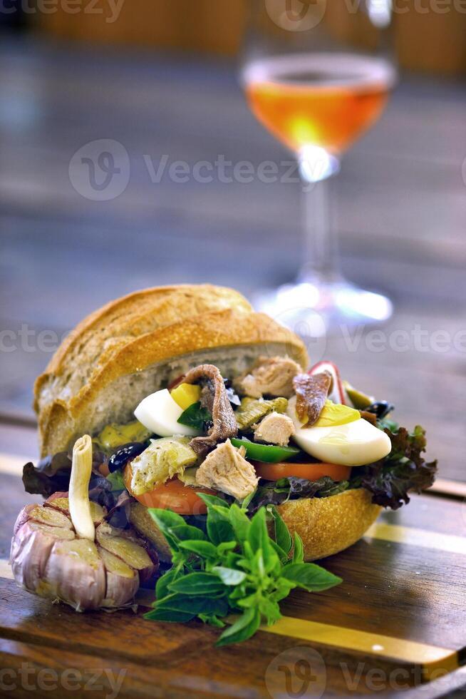 Pan Bagnat, French sandwich with tuna, aliche, tomato, garlic, lettuce, egg and mustard on bread photo