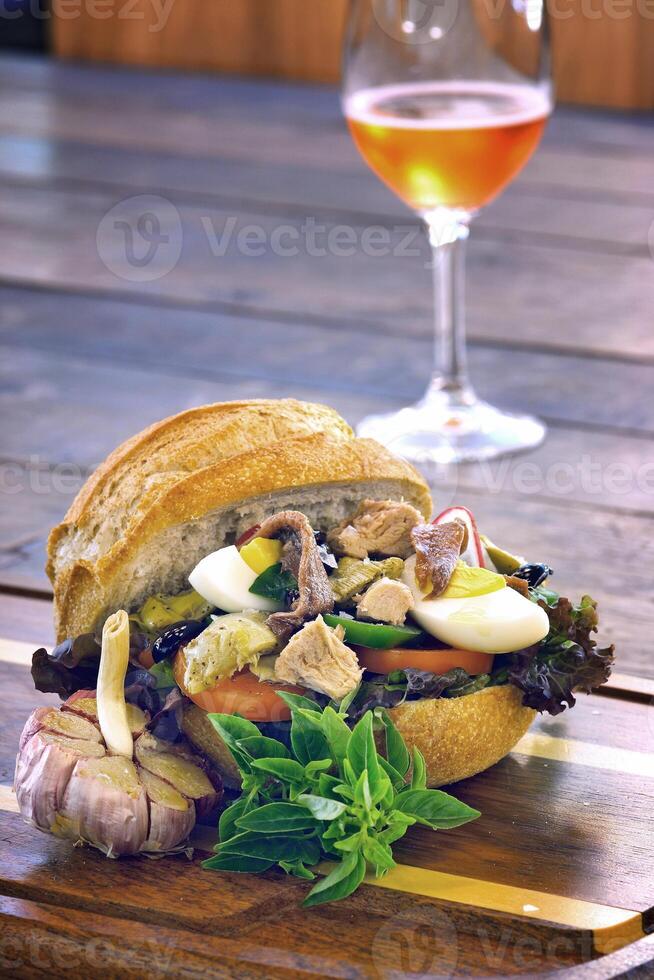 Pan Bagnat, French sandwich with tuna, aliche, tomato, garlic, lettuce, egg and mustard on bread photo