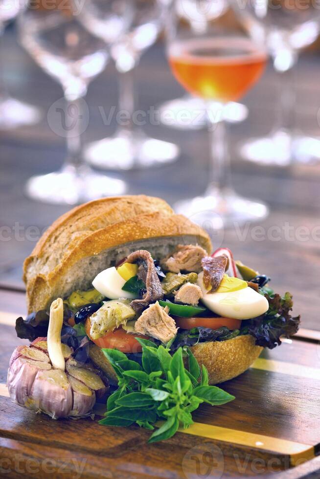 Pan Bagnat, French sandwich with tuna, aliche, tomato, garlic, lettuce, egg and mustard on bread photo