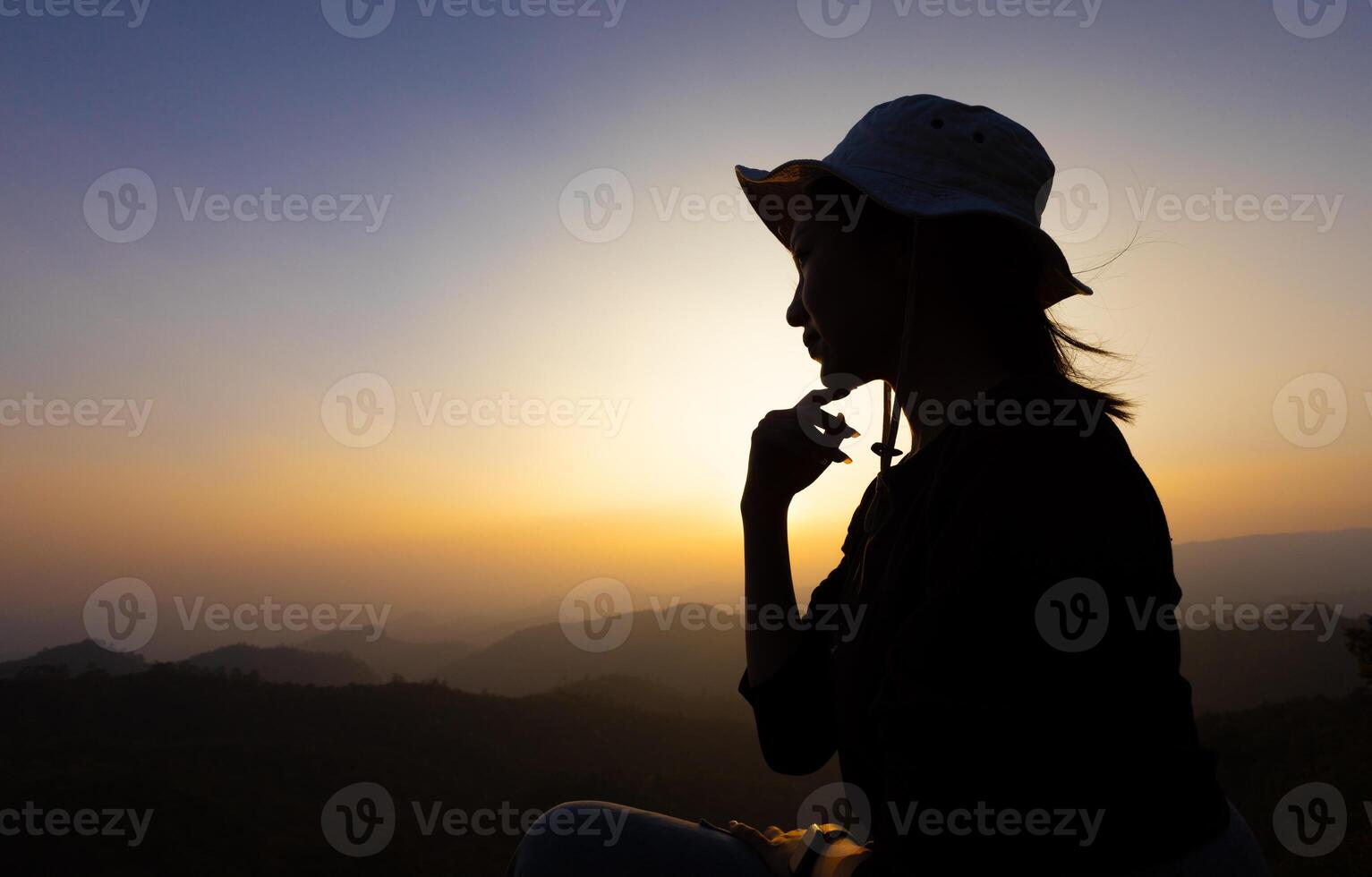 Silhouette of woman sitting on mountain at sunset photo