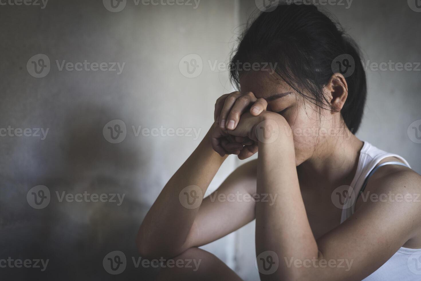 el depresión mujer sentar en el piso, adolescente niña con depresión sentado solo en el piso en el oscuro habitación. foto