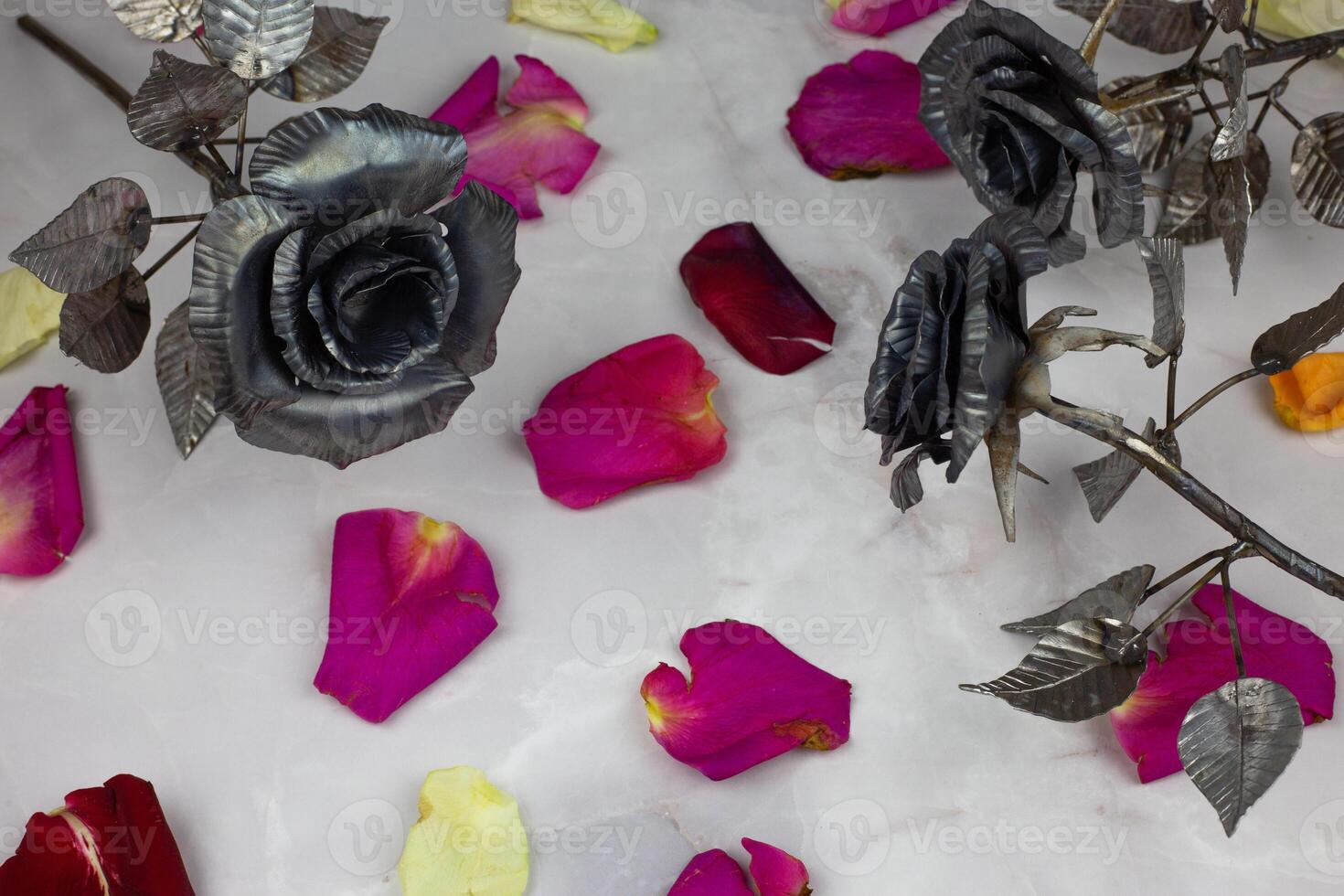 Metal rose buds in scattered leaves of living roses on white background photo