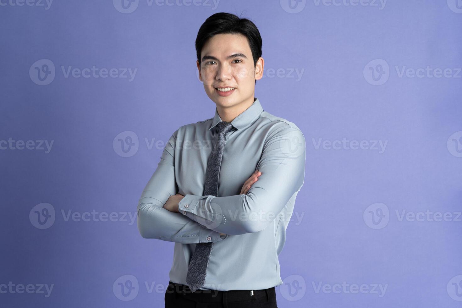 Portrait of Asian male businessman posing on purple background photo