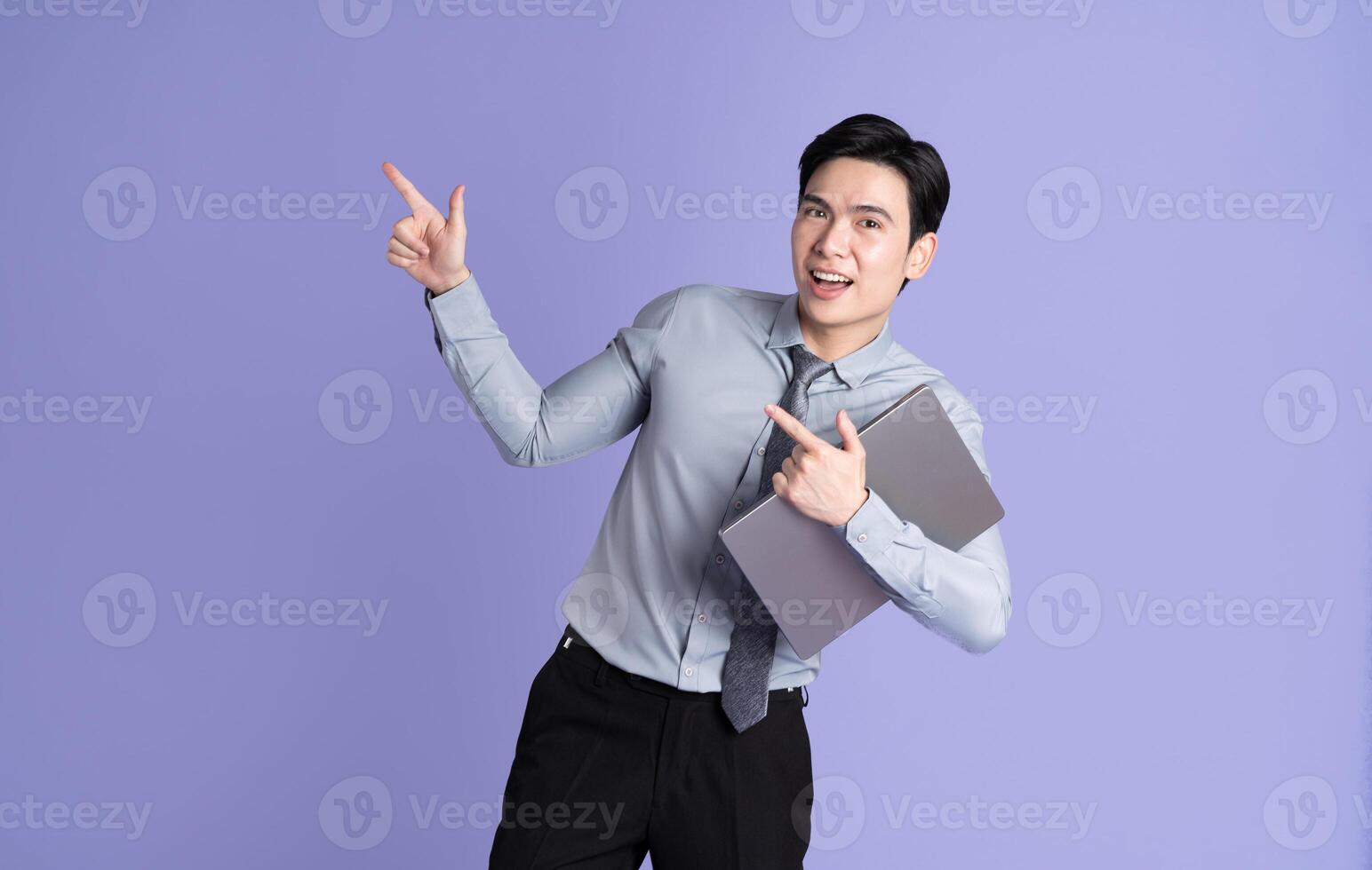 Portrait of Asian male businessman posing on purple background photo