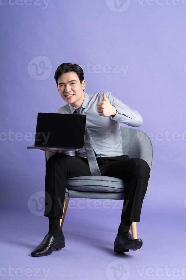 Portrait of Asian business man sitting on sofa, isolated on purple background photo