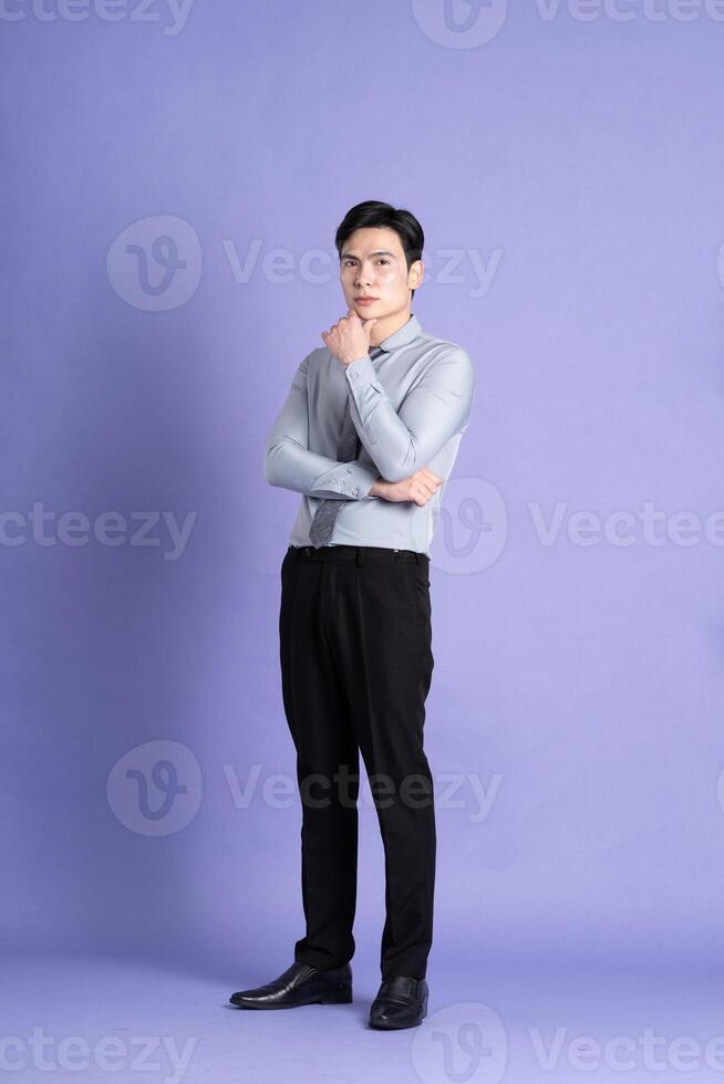 Portrait of Asian male businessman standing and posing on purple background photo