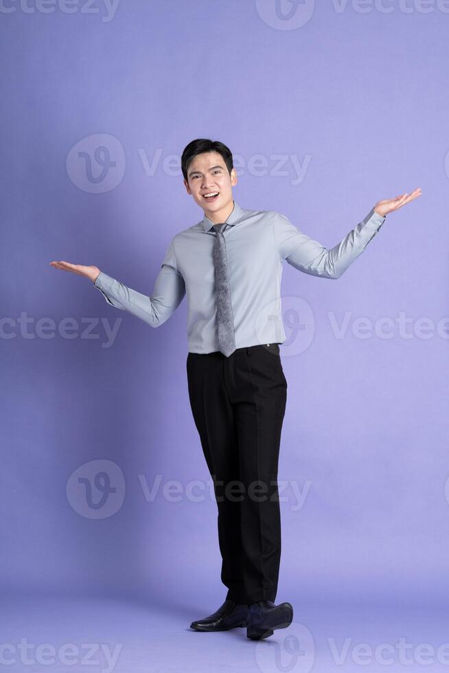 Portrait of Asian male businessman standing and posing on purple background photo