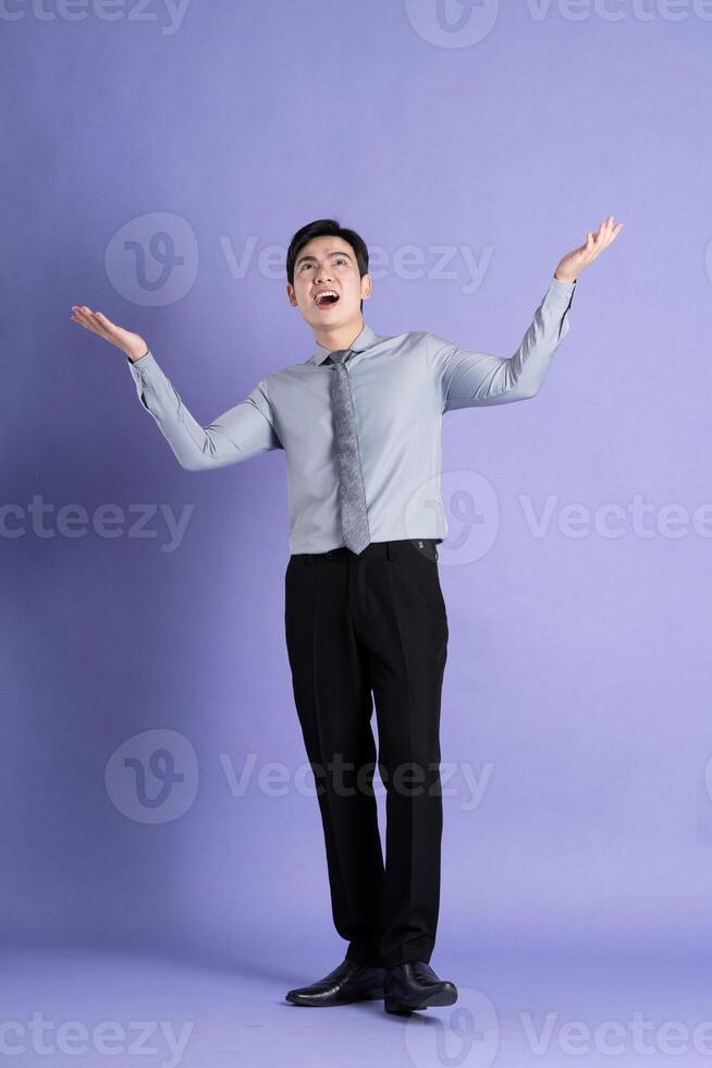 Portrait of Asian male businessman standing and posing on purple background photo