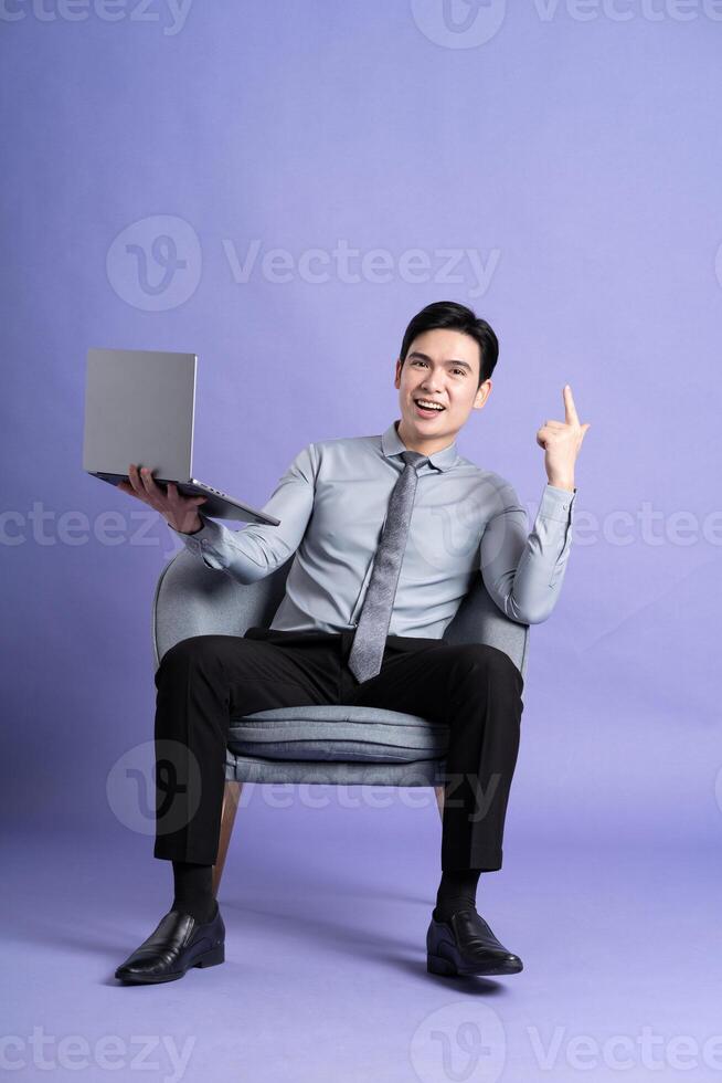 Portrait of Asian business man sitting on sofa, isolated on purple background photo