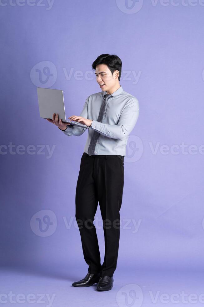 Portrait of Asian male businessman standing and posing on purple background photo