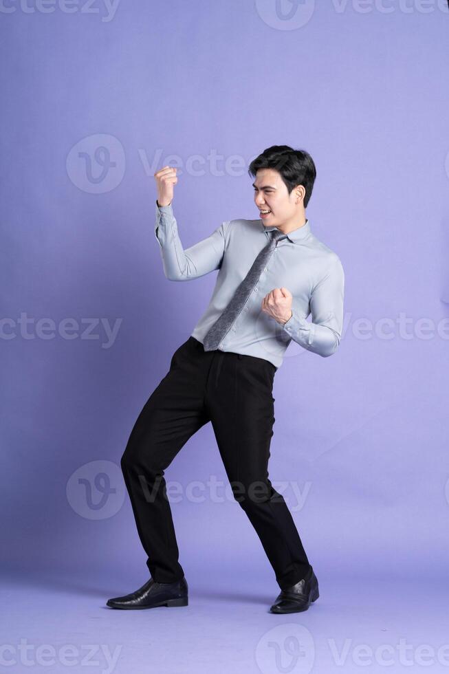 Portrait of Asian male businessman standing and posing on purple background photo