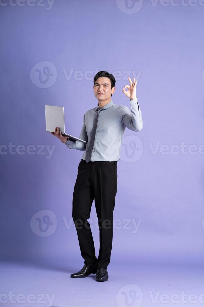 Portrait of Asian male businessman standing and posing on purple background photo