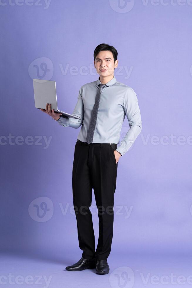 Portrait of Asian male businessman standing and posing on purple background photo