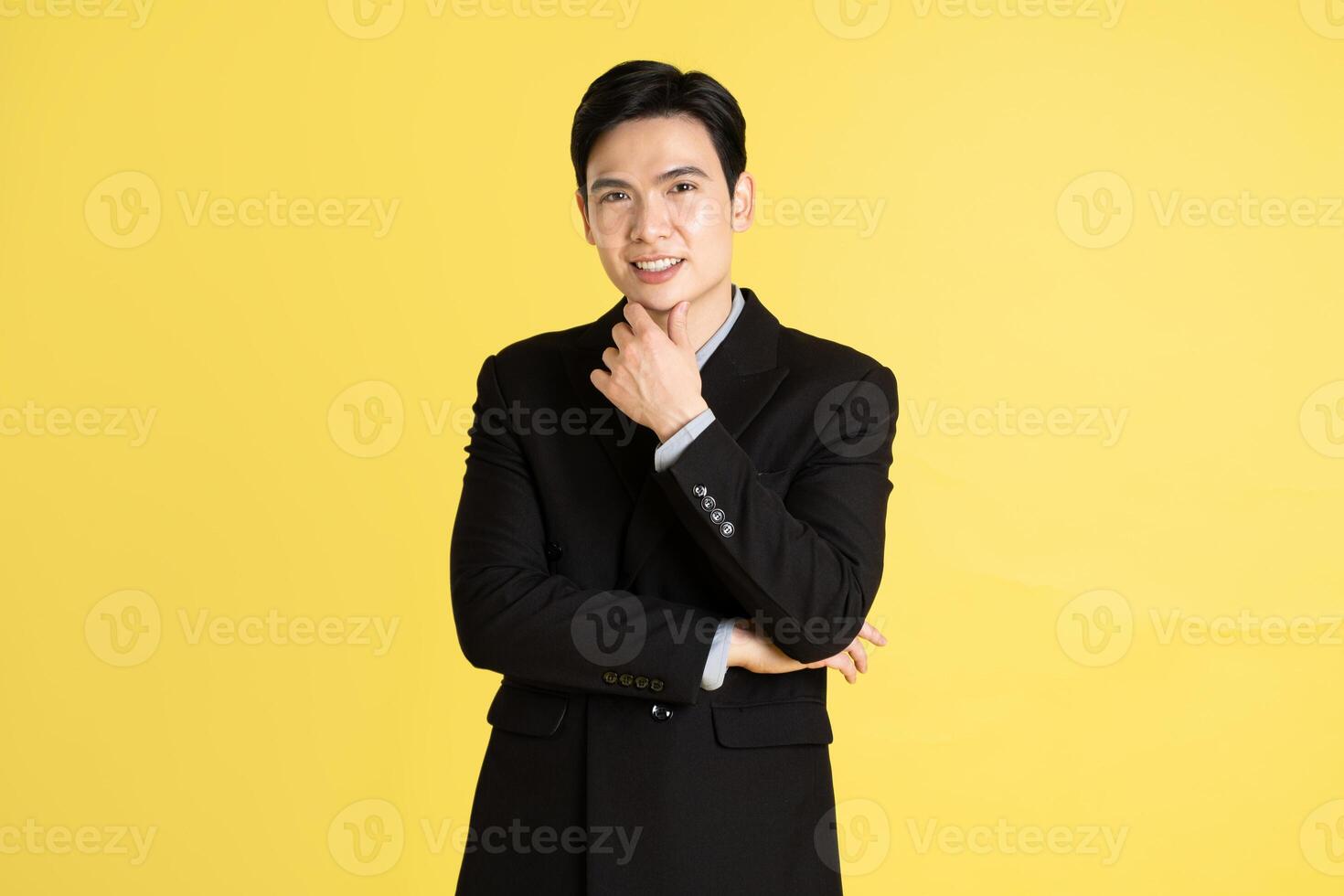 Portrait of Asian male businessman. wearing a suit and posing on a yellow background photo
