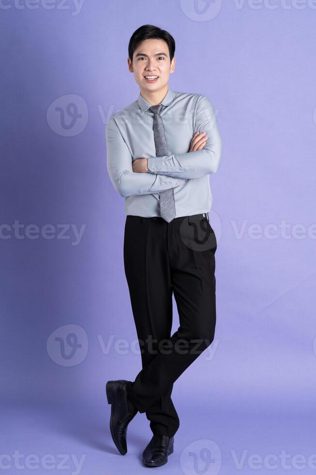 Portrait of Asian male businessman standing and posing on purple background photo