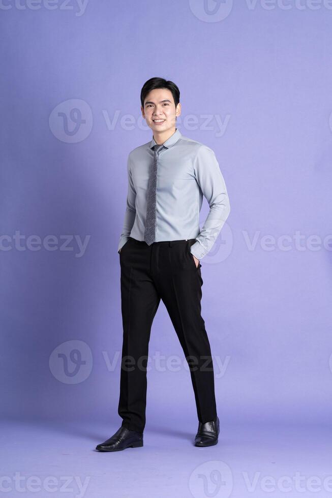 Portrait of Asian male businessman standing and posing on purple background photo