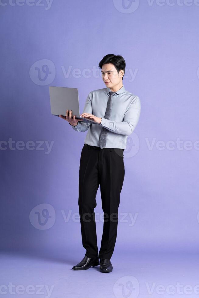 Portrait of Asian male businessman standing and posing on purple background photo