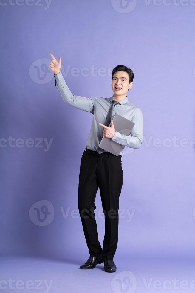 Portrait of Asian male businessman standing and posing on purple background photo