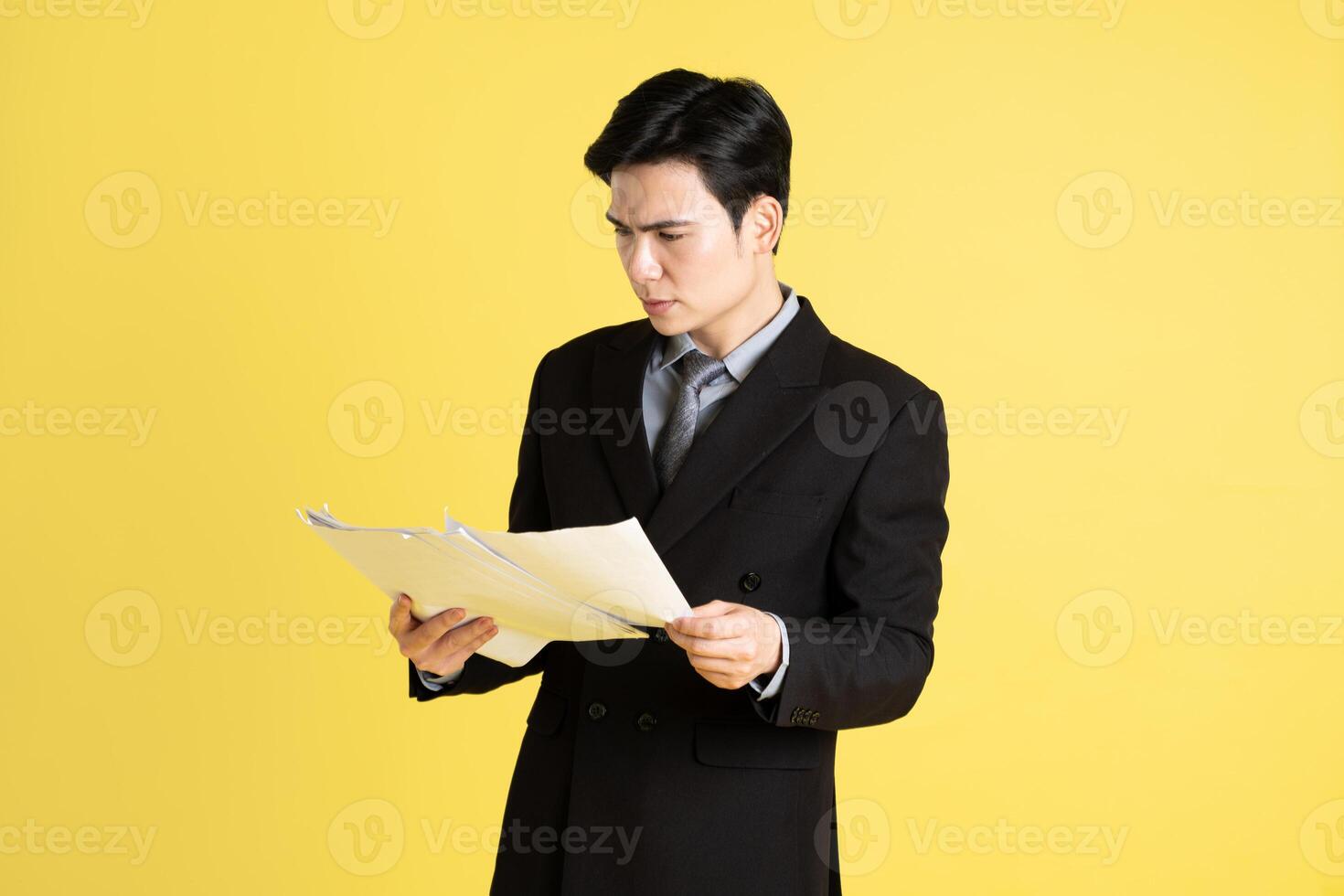 Portrait of Asian male businessman. wearing a suit and posing on a yellow background photo