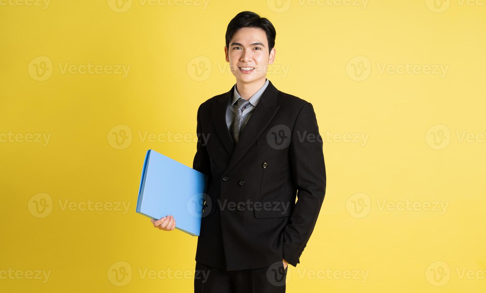 Portrait of Asian male businessman. wearing a suit and posing on a yellow background photo